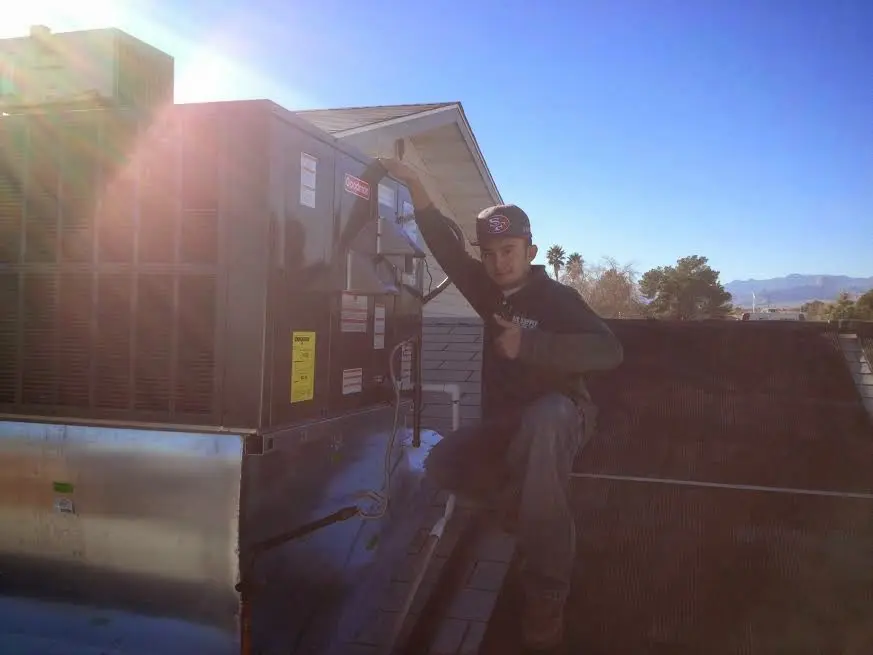 HVAC technician performing Heat Pump Repair on a rooftop unit in Versailles